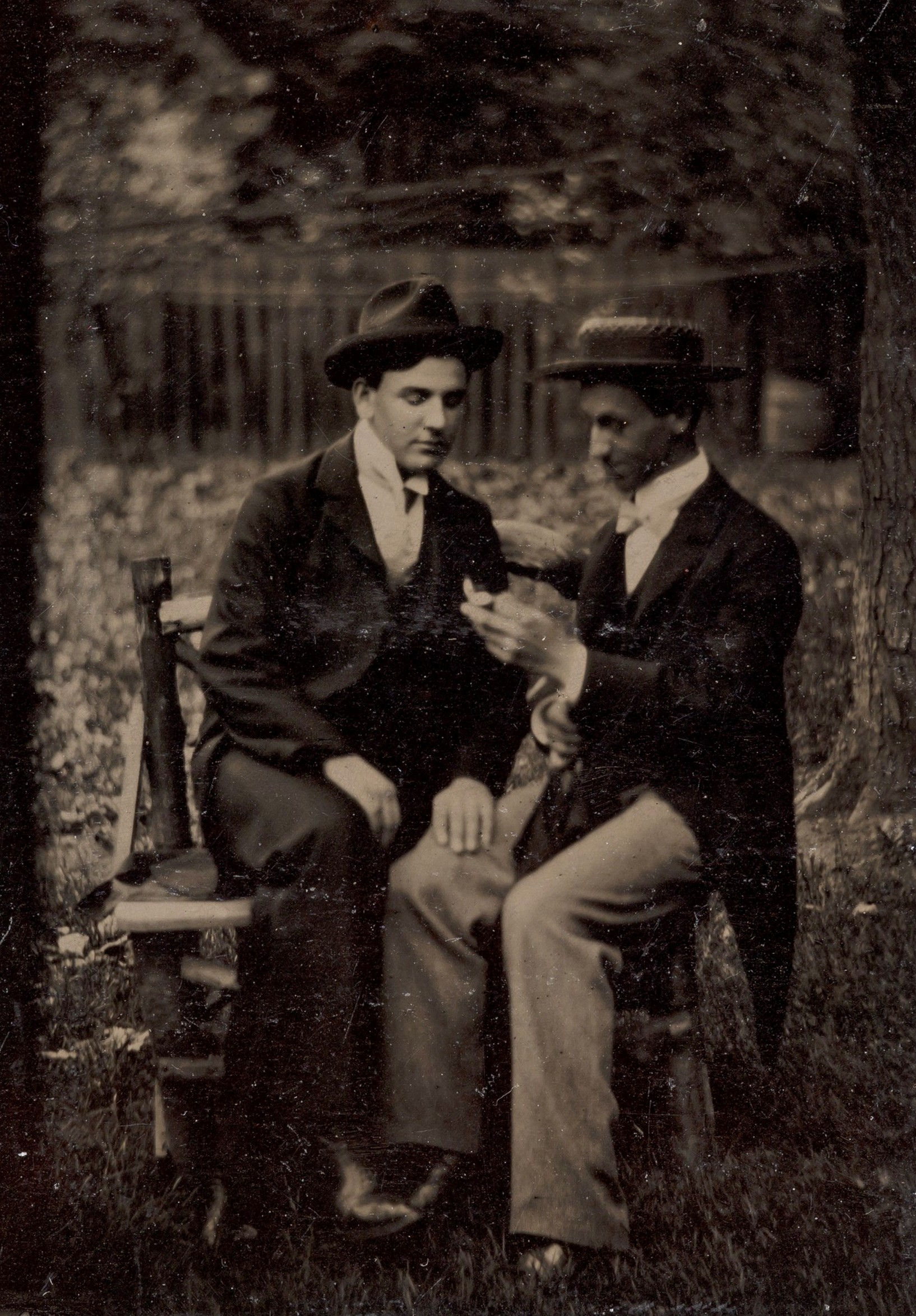 Двое мужчин, сидящих на скамье, один положил руку на ногу другого; тинтайп, фотография неизвестного автора, 1870–1880-е годы