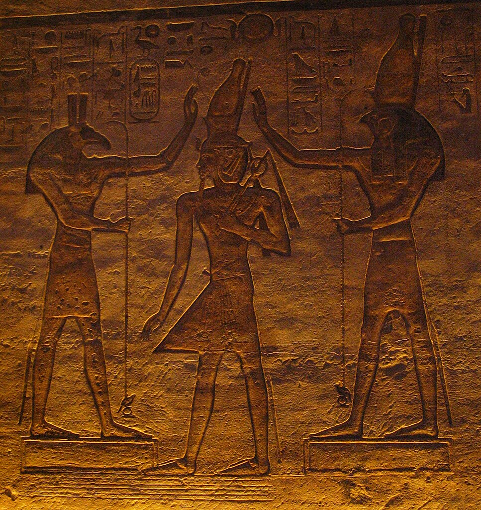 Set (izquierda) y Horus (derecha) colocan la corona real sobre la cabeza de Ramsés II. Bajorrelieve del Gran Templo de Abu Simbel, XIX dinastía.