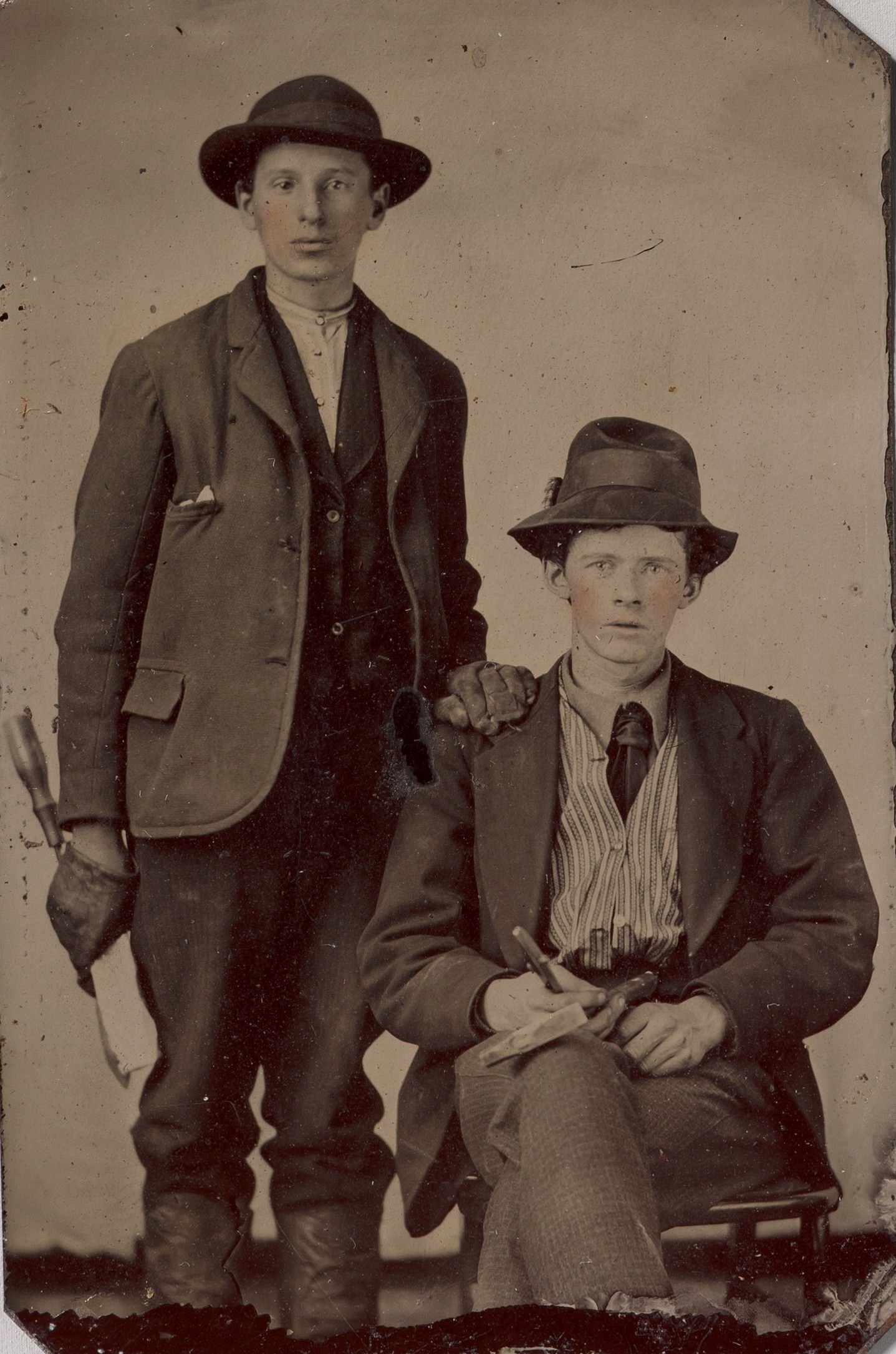 Dois jovens — um sentado, outro de pé — com ferramentas de carpintaria; ferrotipia de autor desconhecido, décadas de 1870–1890